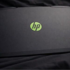HP Laptop with Green Emblem on Black Surface